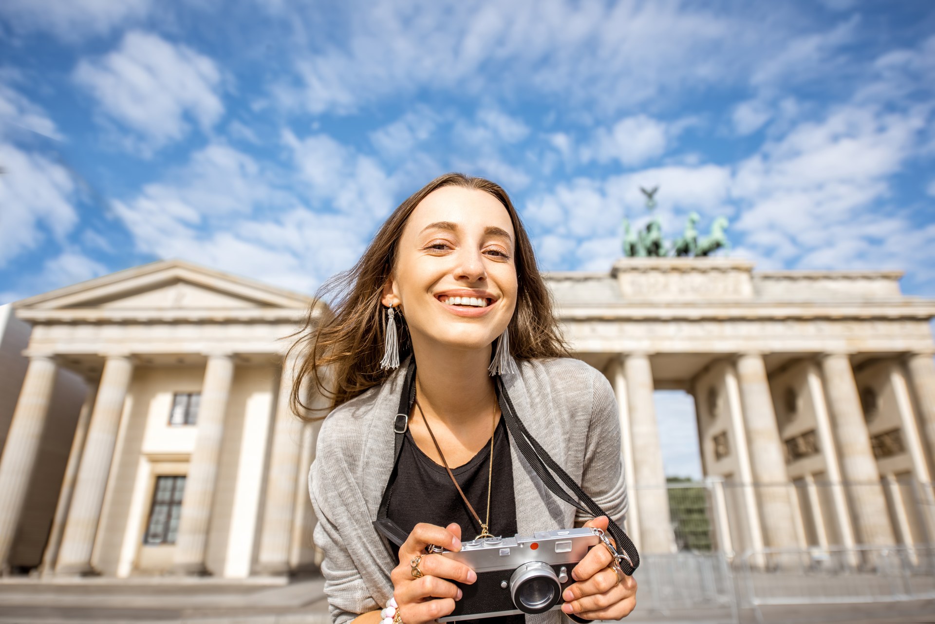 Uśmiechnięta turystka z aparatem przed Bramą Brandenburską w Berlinie